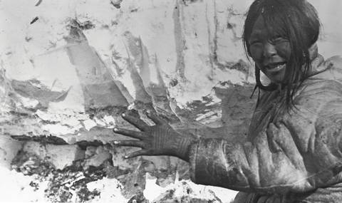 Milukkattuk, Dolphin and Union Strait Inuk woman, wife of Avrunna (36926), front view with hood down, arm and hand extended showing tattooed hand, Bernard Harbour, N.W.T. (Nunavut).