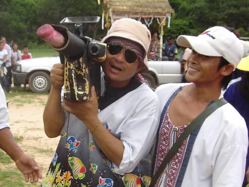 Palad khik (phallic waist charm) — Cameraman (with fake camera) at village Rocket Festival shoots author, Pawyi Lee