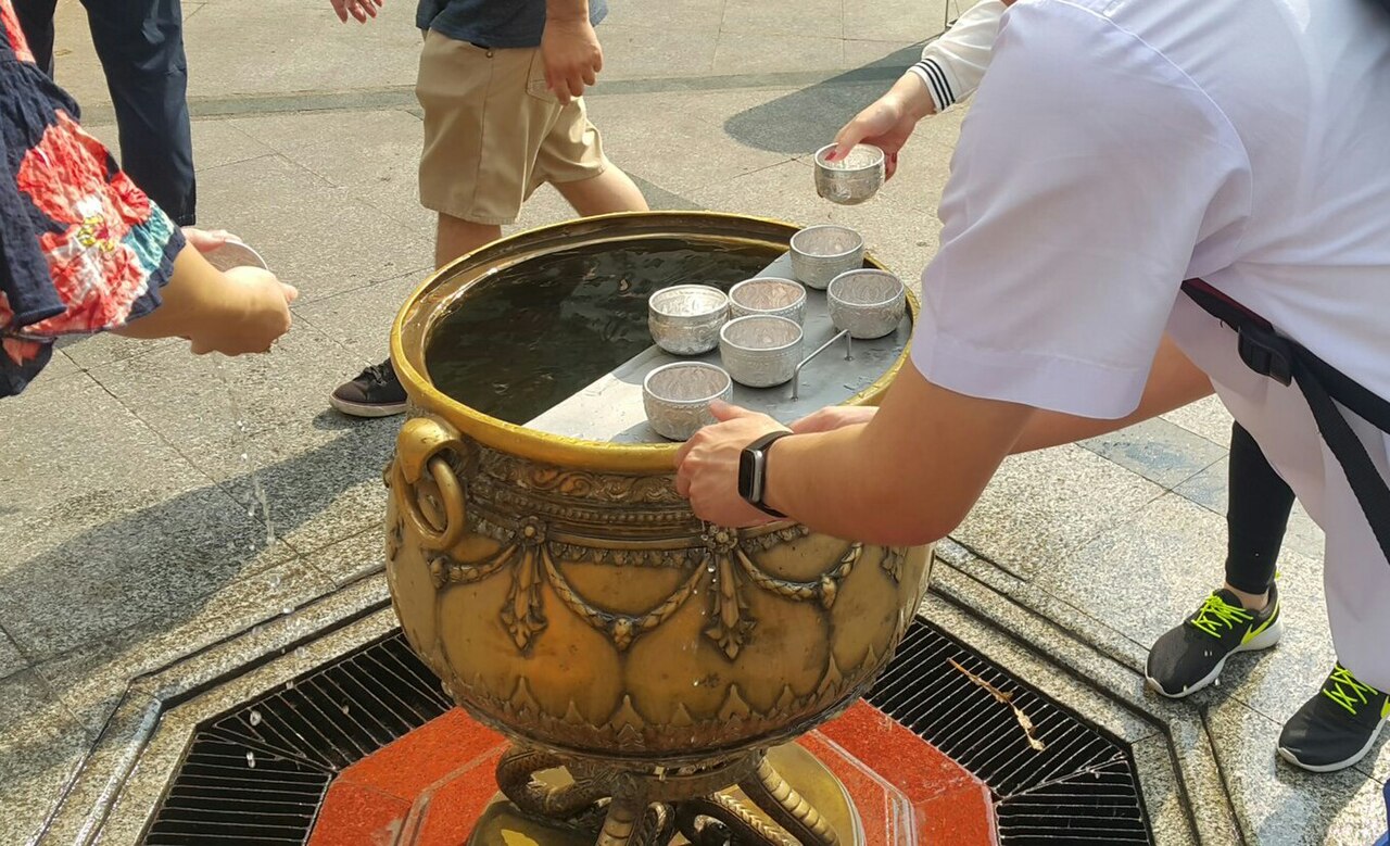 Four-faced Brahma pendant — A Thai student pouring the holy water on his two hands at Erawan shrine