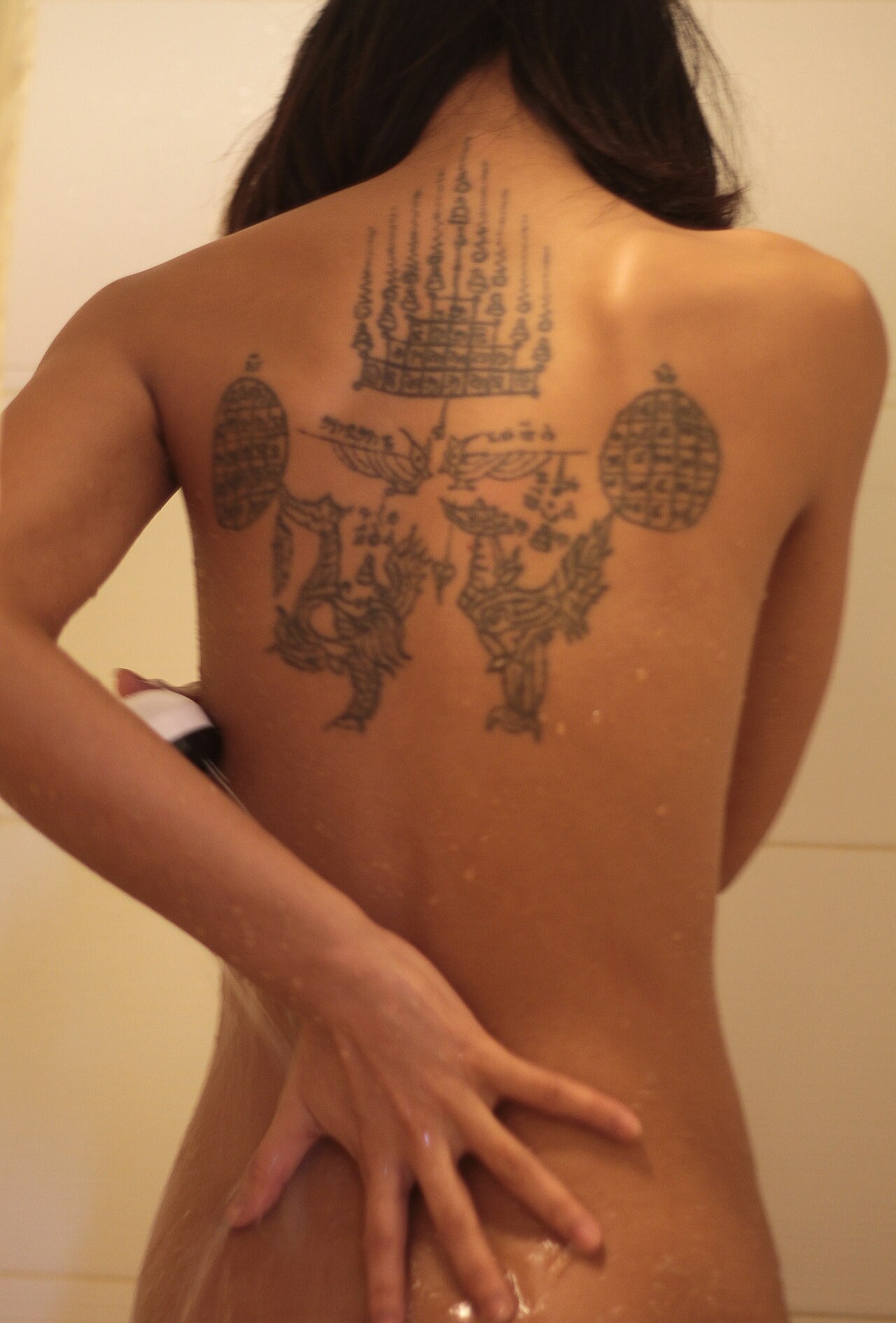 Khmer yantra cloth — A tattoed Cambodian woman having a shower.