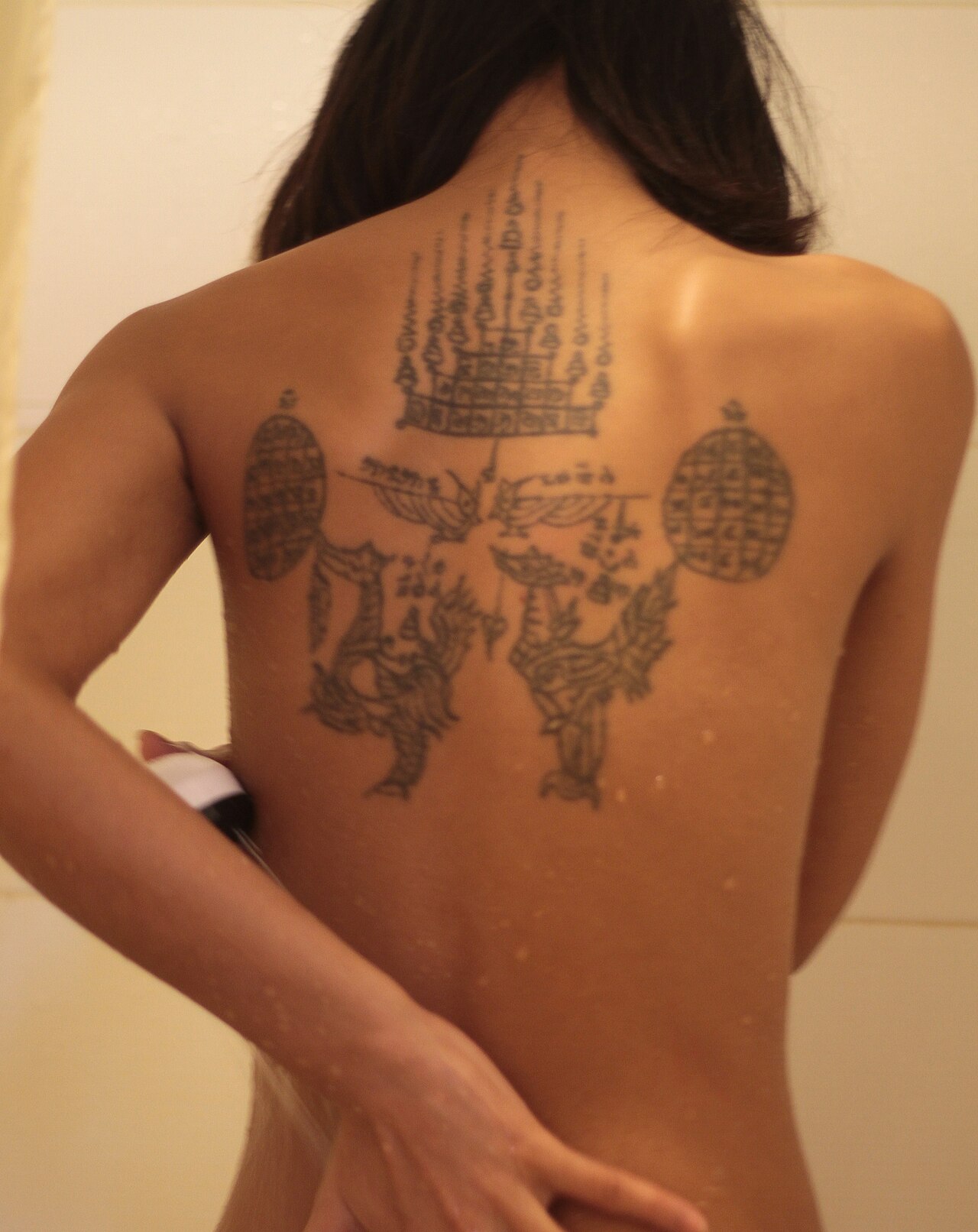 Khmer yantra cloth — A tattoed Cambodian woman having a shower.